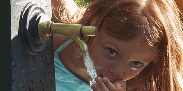 Niña bebe en una fuente en el Día Mundial de la Fontanería